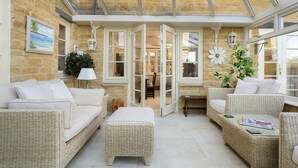 A cozy room with wicker furniture, a glass ceiling, and a view of the interior. - Chipping Campden Modern House, Garden, upstairs/downstairs bedrooms/bathrooms.  (Chipping Campden)