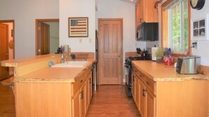 Una cocina con armarios de madera, un lavamanos, una estufa y un microondas.