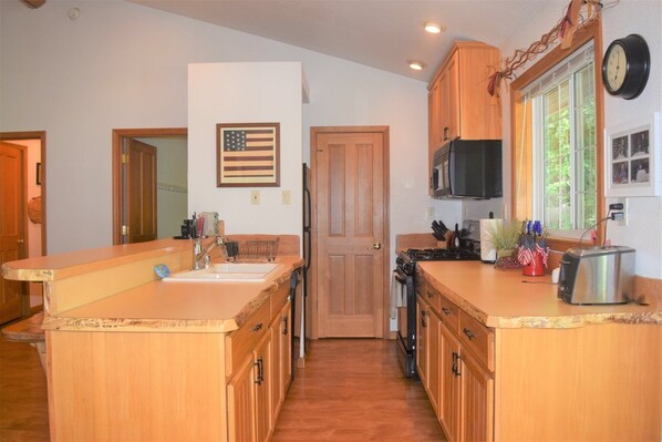 A kitchen with wooden cabinets, a sink, a stove, and a microwave.