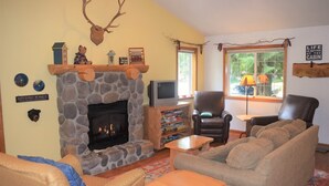 Una sala de estar acogedora con chimenea de piedra, asientos cómodos y un televisor.
