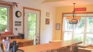 Una cocina con una barra de madera y taburetes, un reloj en la pared y un candelabro.