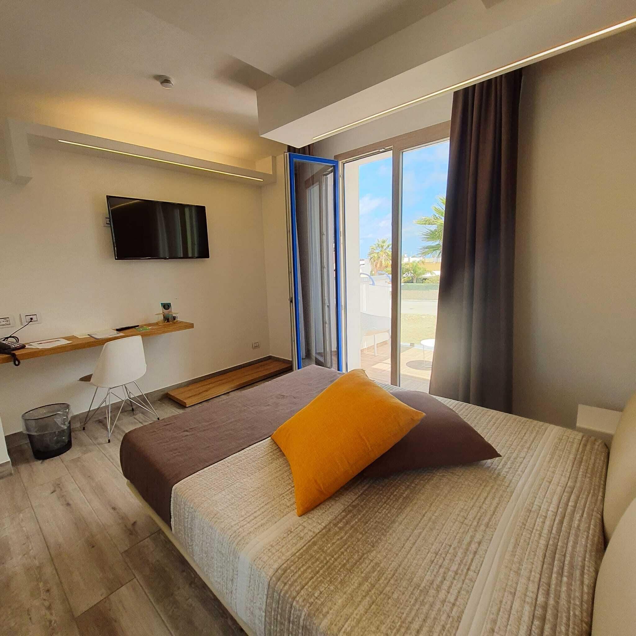 Una habitación de hotel moderna con una cama, un escritorio, una silla y un televisor.