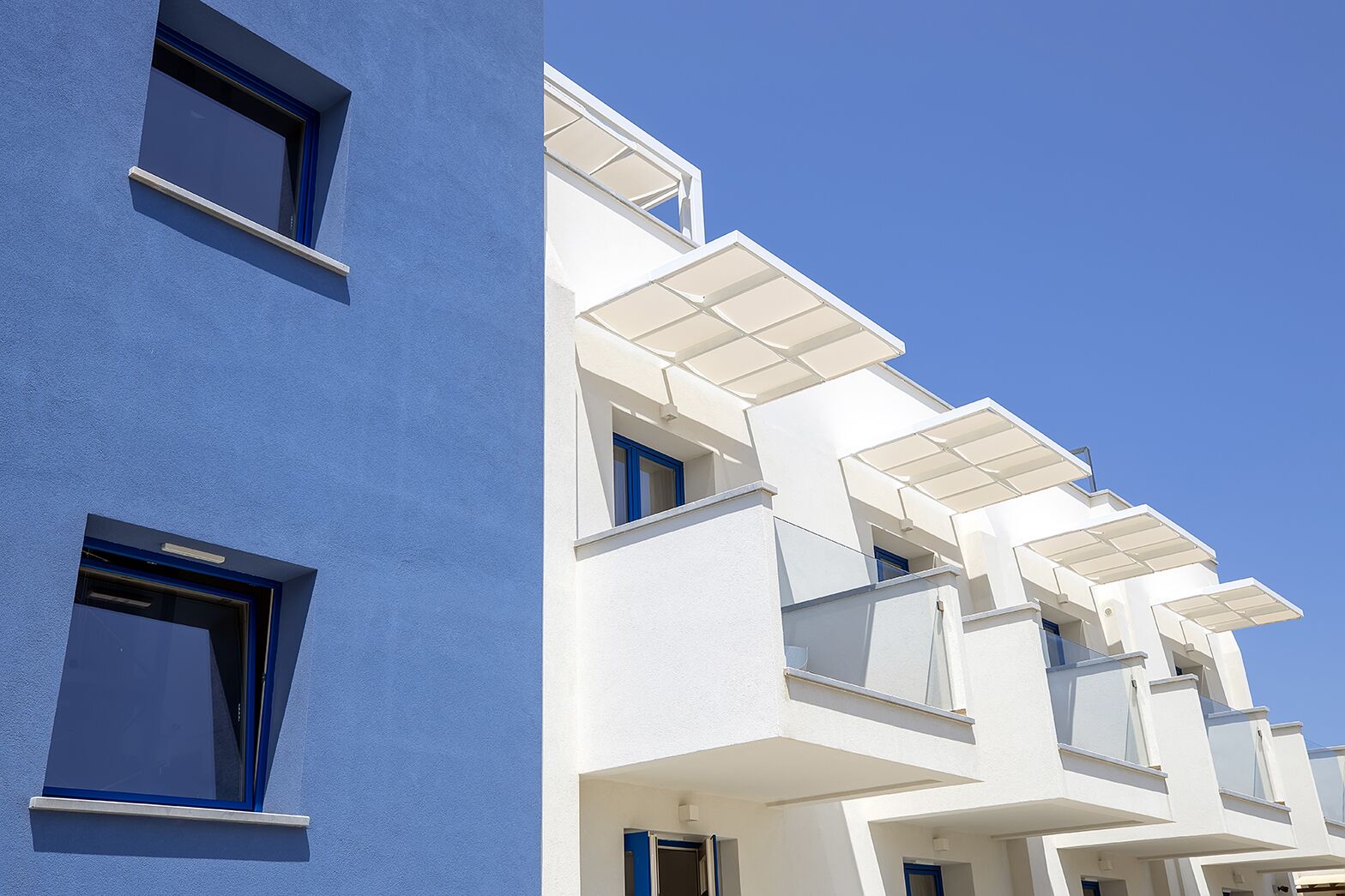 A modern building with a blue facade and white balconies.