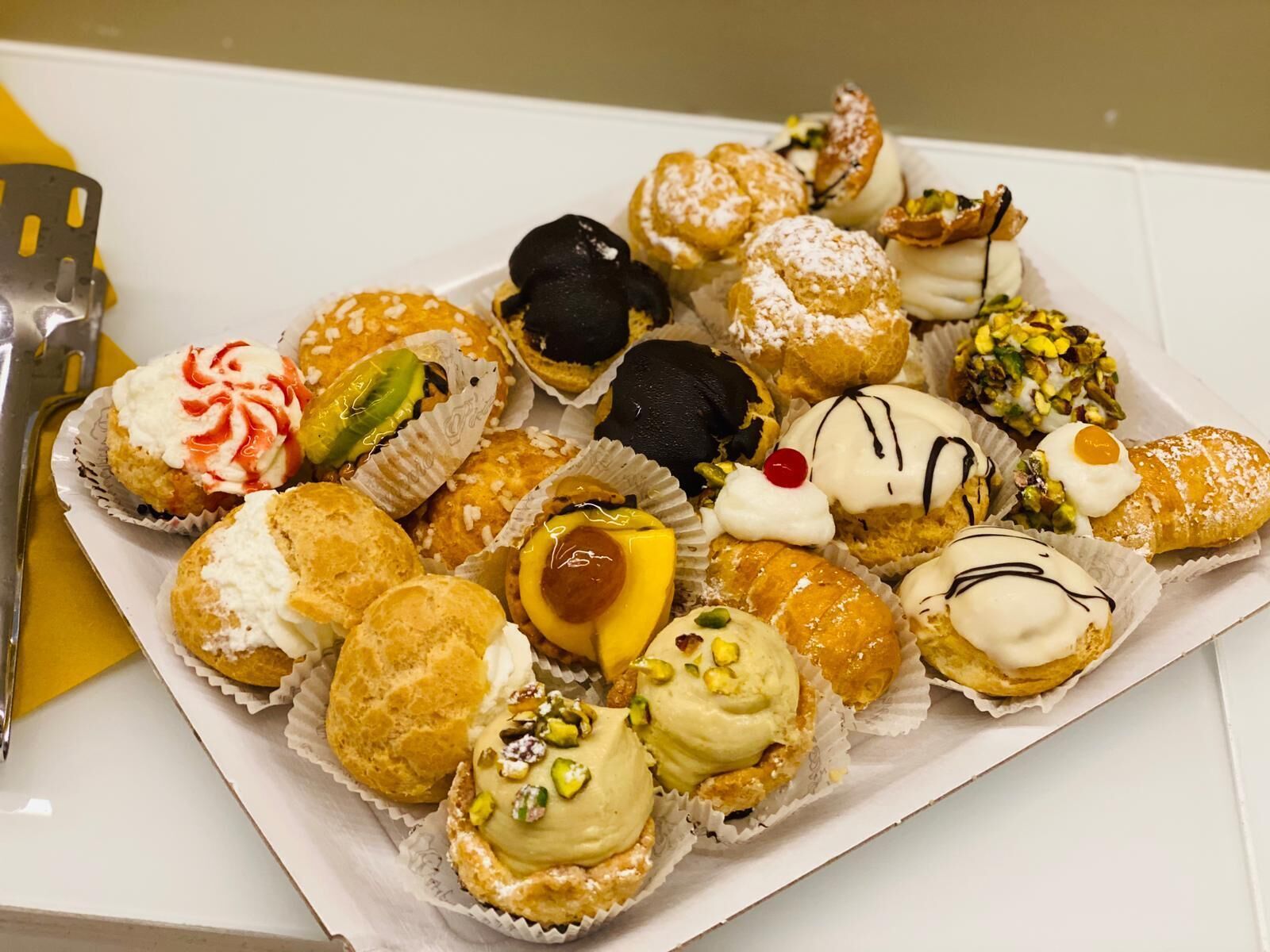 A tray of assorted pastries including cream puffs, éclairs, and other desserts.