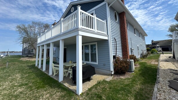 A two-story house with a covered porch, a brick chimney, and a view of the lake. - CANAL FRONT - GREAT VIEWS - 5 BDRM, 3&1/2 BATHS, 2 KINGS, GOLF, RELAX... (Ocean Pines)