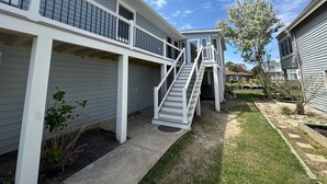 A residential building with a covered outdoor area, a staircase leading to a second floor, and a small garden. - CANAL FRONT - GREAT VIEWS - 5 BDRM, 3&1/2 BATHS, 2 KINGS, GOLF, RELAX... (Ocean Pines)