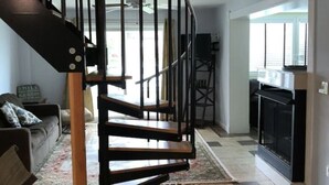 A modern living room with a black spiral staircase, a fireplace, and a checkered floor. - CANAL FRONT - GREAT VIEWS - 5 BDRM, 3&1/2 BATHS, 2 KINGS, GOLF, RELAX... (Ocean Pines)
