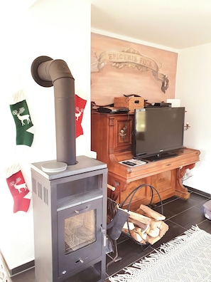 Cozy living room with a wood-burning stove, television, and fireplace mantel.