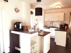 Enjoy cooking in this well-lit kitchen with a central island, coffee maker, and sleek countertop.