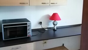 Eine Küche mit Holzausstattung, einem Toasterofen, einer roten Lampe und einem kleinen Regal.