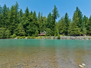 Eine Hütte, umgeben von dichtem Wald und einem klaren See.
