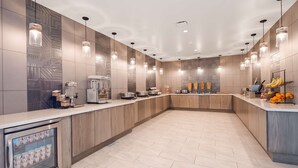 Una cocina moderna con una isla central, equipada con cafetera, tostadora y una exhibición de frutas.