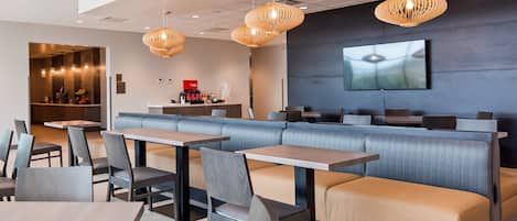 A modern restaurant with a long counter, cushioned seating, and pendant lighting.