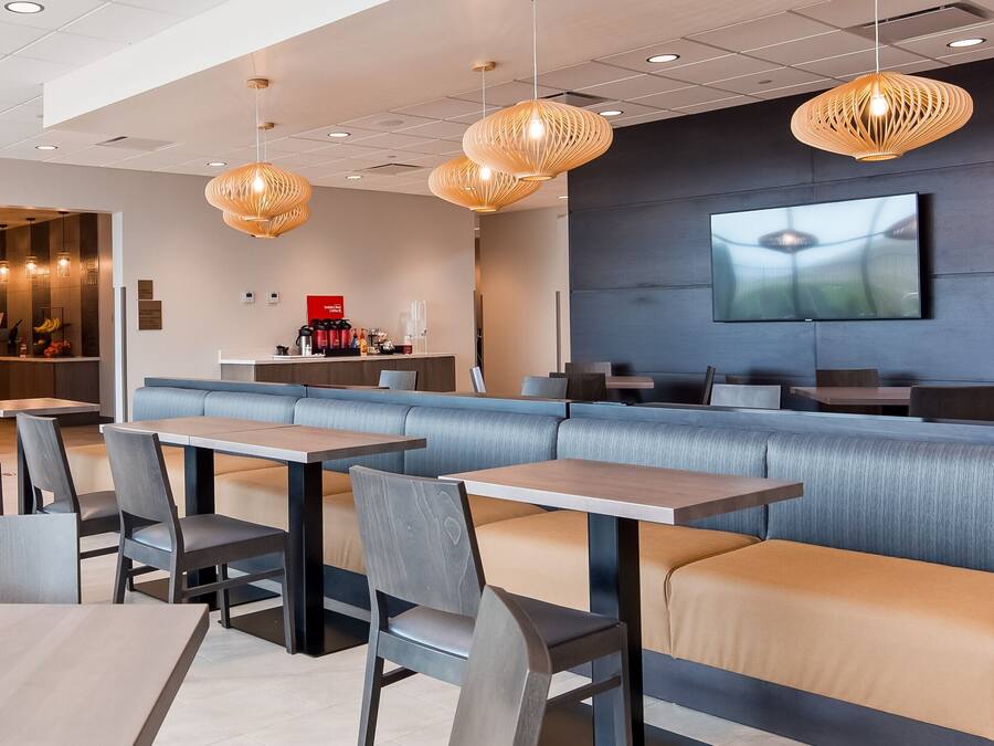 A modern restaurant with a long counter, cushioned seating, and pendant lighting.