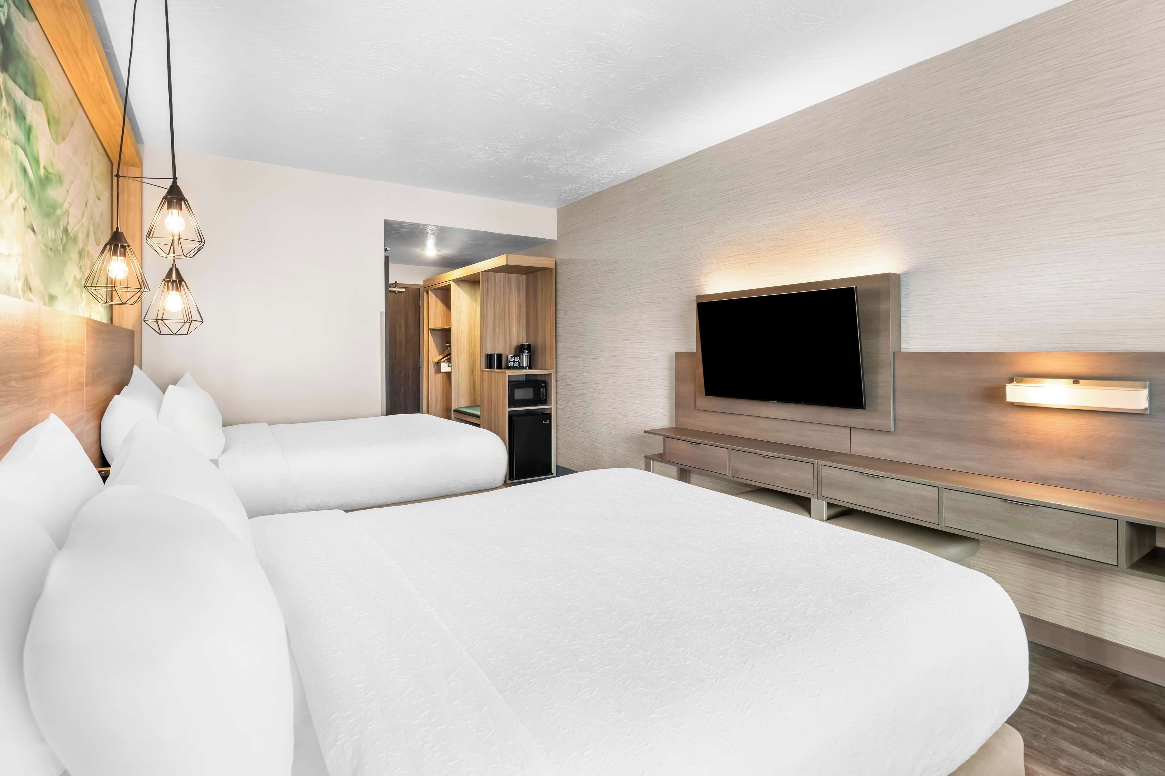 Een hotelkamer met twee bedden, een televisie en een kitchenette.