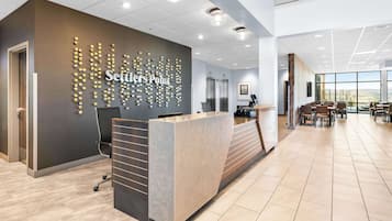 A modern reception area with a reception desk, a wall-mounted sign, and a seating area with tables and chairs.