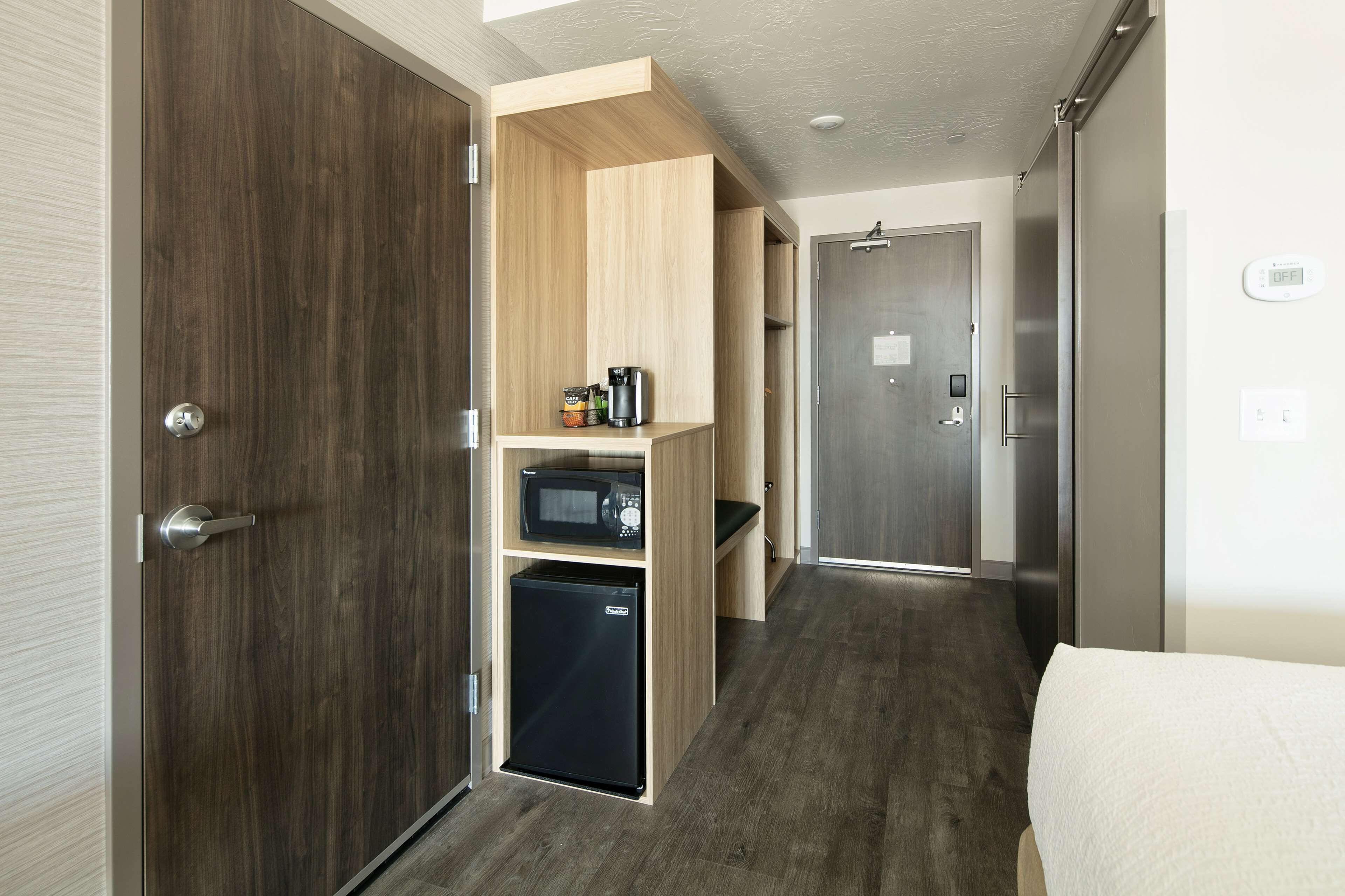 A compact kitchen with a microwave, refrigerator, and wooden cabinets.