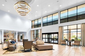 A spacious lobby with a modern chandelier, comfortable seating, large windows, and a view of the outdoors. - Best Western Plus Settlers Point (Washington)
