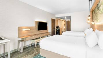Une chambre d’hôtel moderne dotée d’un grand lit, d’un téléviseur à écran plat fixé sur un panneau en bois, d’un bureau avec une chaise et d’une petite table.