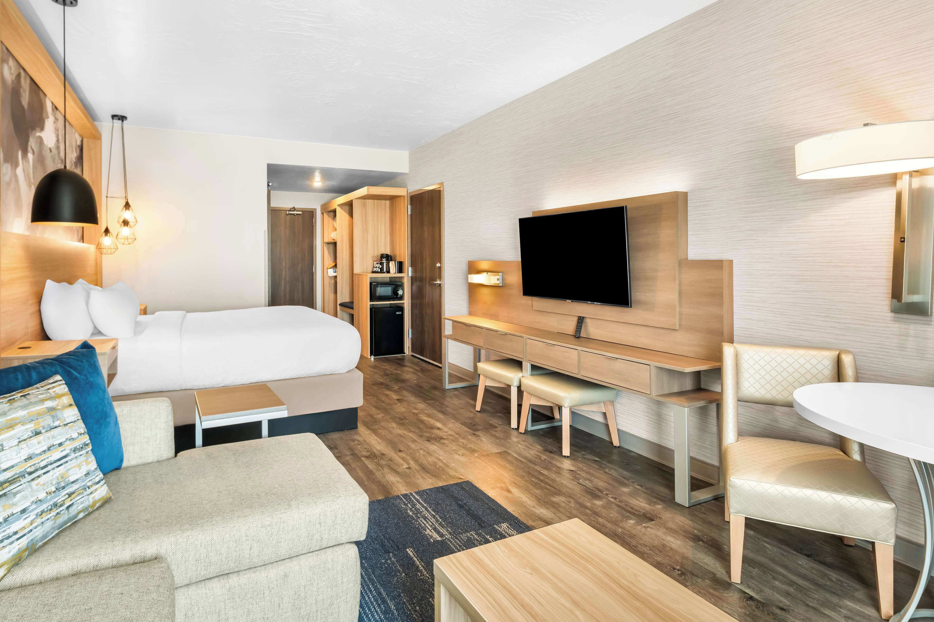 Une chambre d’hôtel moderne équipée d’un lit, d’un bureau, d’une télévision et d’un coin salon.