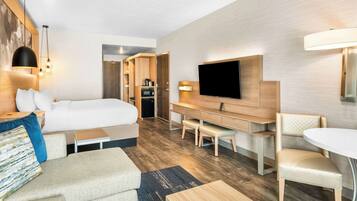 Une chambre d’hôtel moderne équipée d’un lit, d’un bureau, d’une télévision et d’un coin salon.
