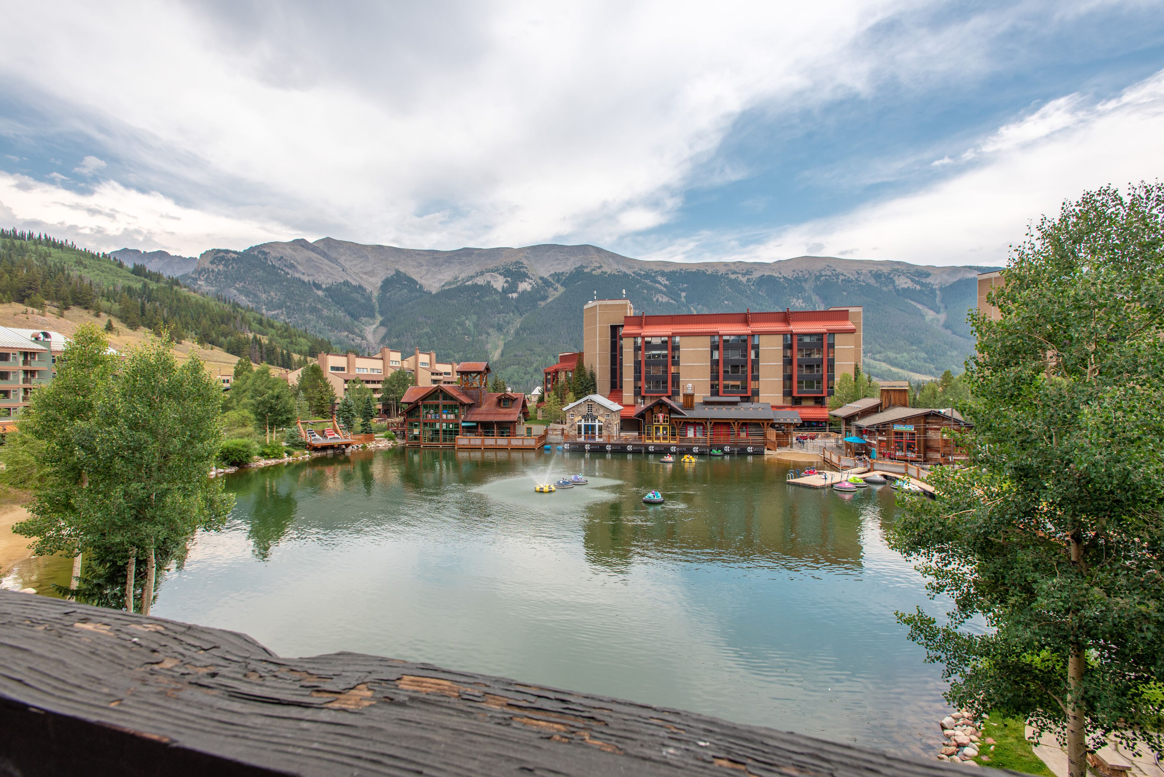 Ein Seehotel mit Gebäuden, Booten und Bergen im Hintergrund.