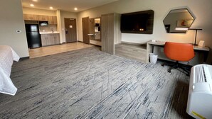 A hotel room with a kitchen area, a TV mounted on the wall, a desk with a chair, and a bed. - Holiday Inn Express & Suites Ft. Smith Airport by IHG (Fort Smith)