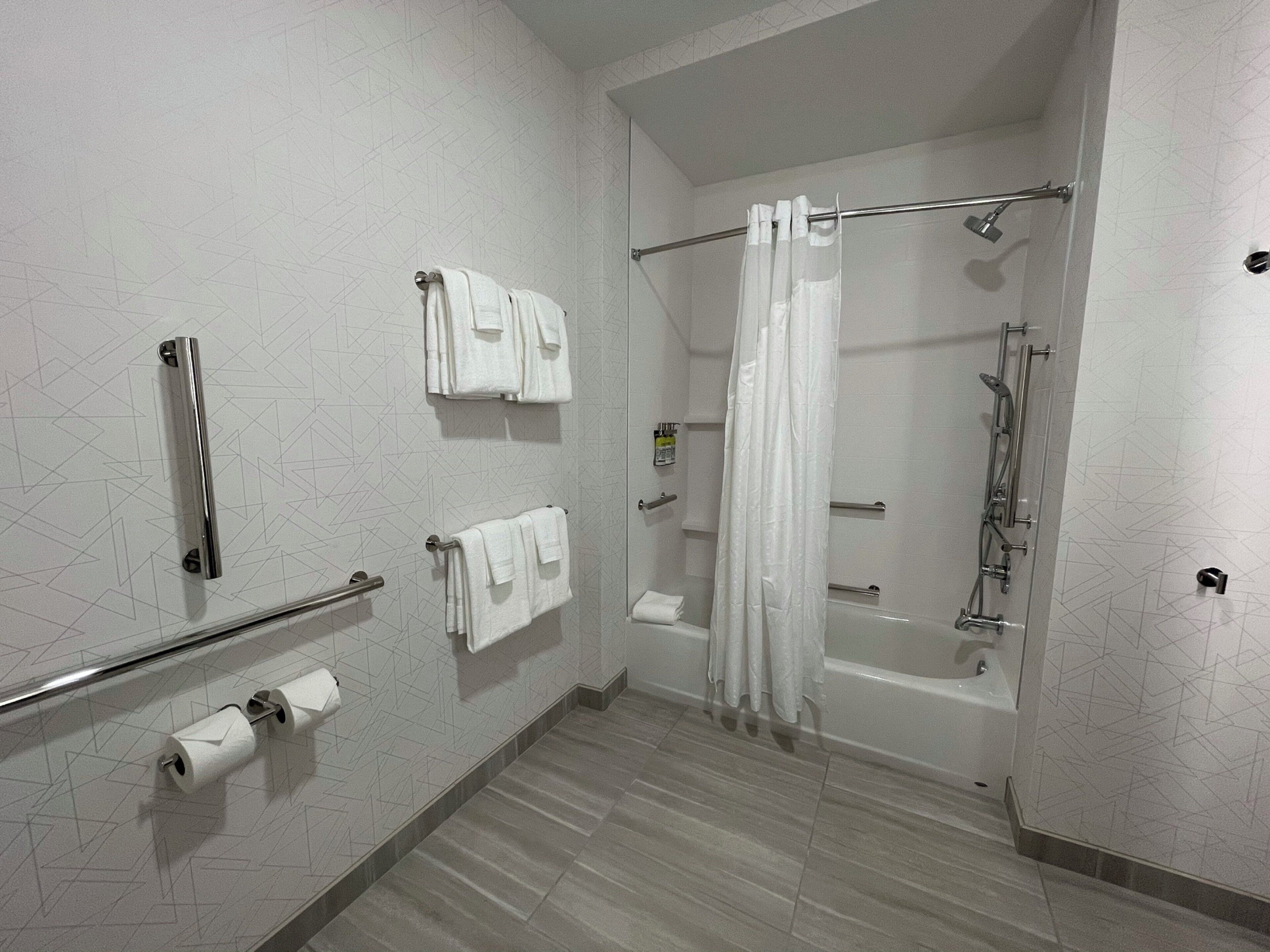 A modern bathroom with a shower, toilet paper, and towels.