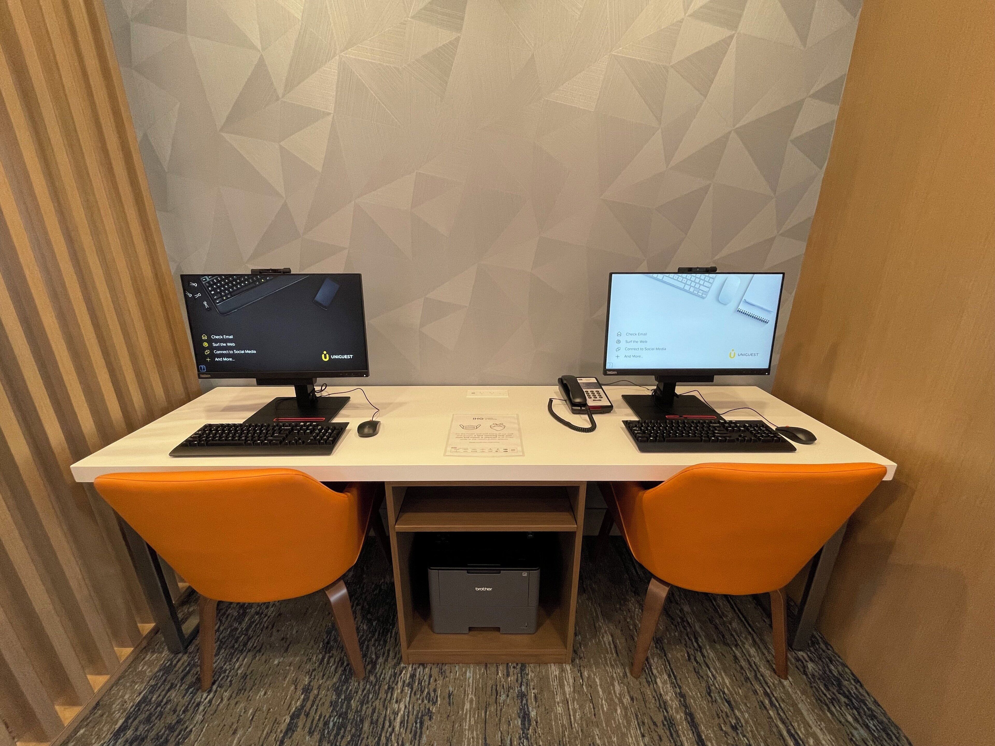 A workspace with two monitors, a keyboard, a mouse, and an orange chair.