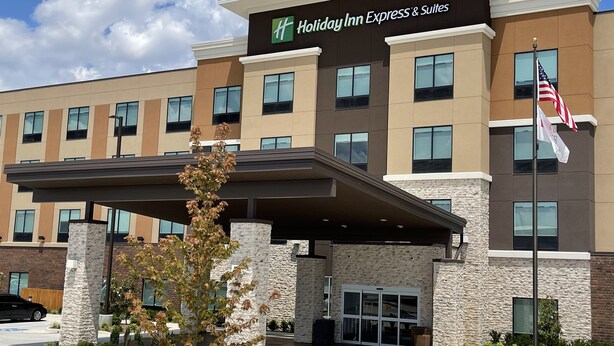Ein Holiday Inn Express & Suites Gebäude mit modernem Design, mit einer Stein Fassade, zahlreichen Fenstern und einem überdachten Eingang.