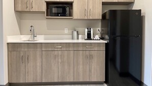 A kitchen with light wood cabinets, a black refrigerator, a microwave, a coffee maker, and a sink. - Holiday Inn Express & Suites Ft. Smith Airport by IHG (Fort Smith)