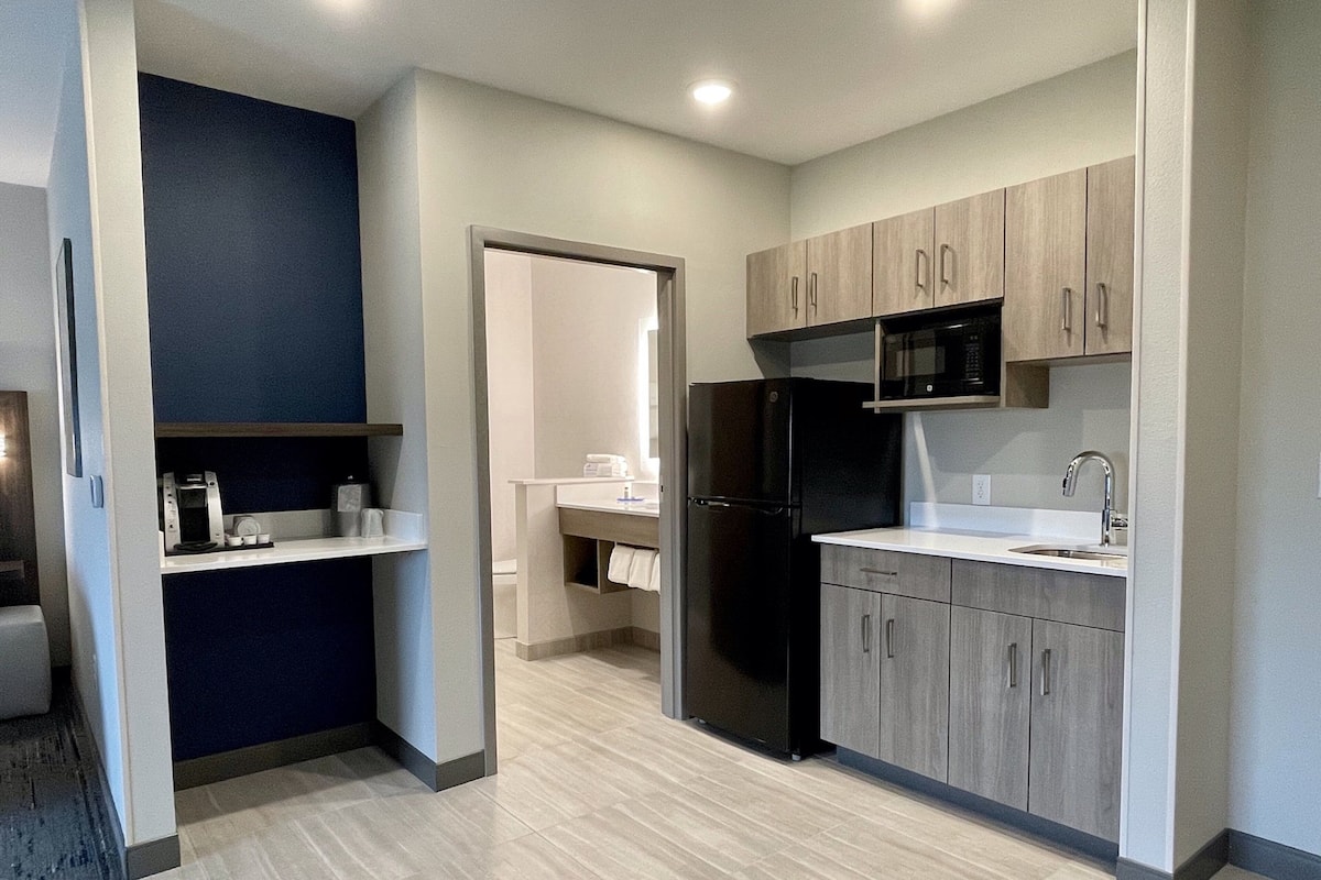 A modern kitchen with a refrigerator, microwave, and sink.