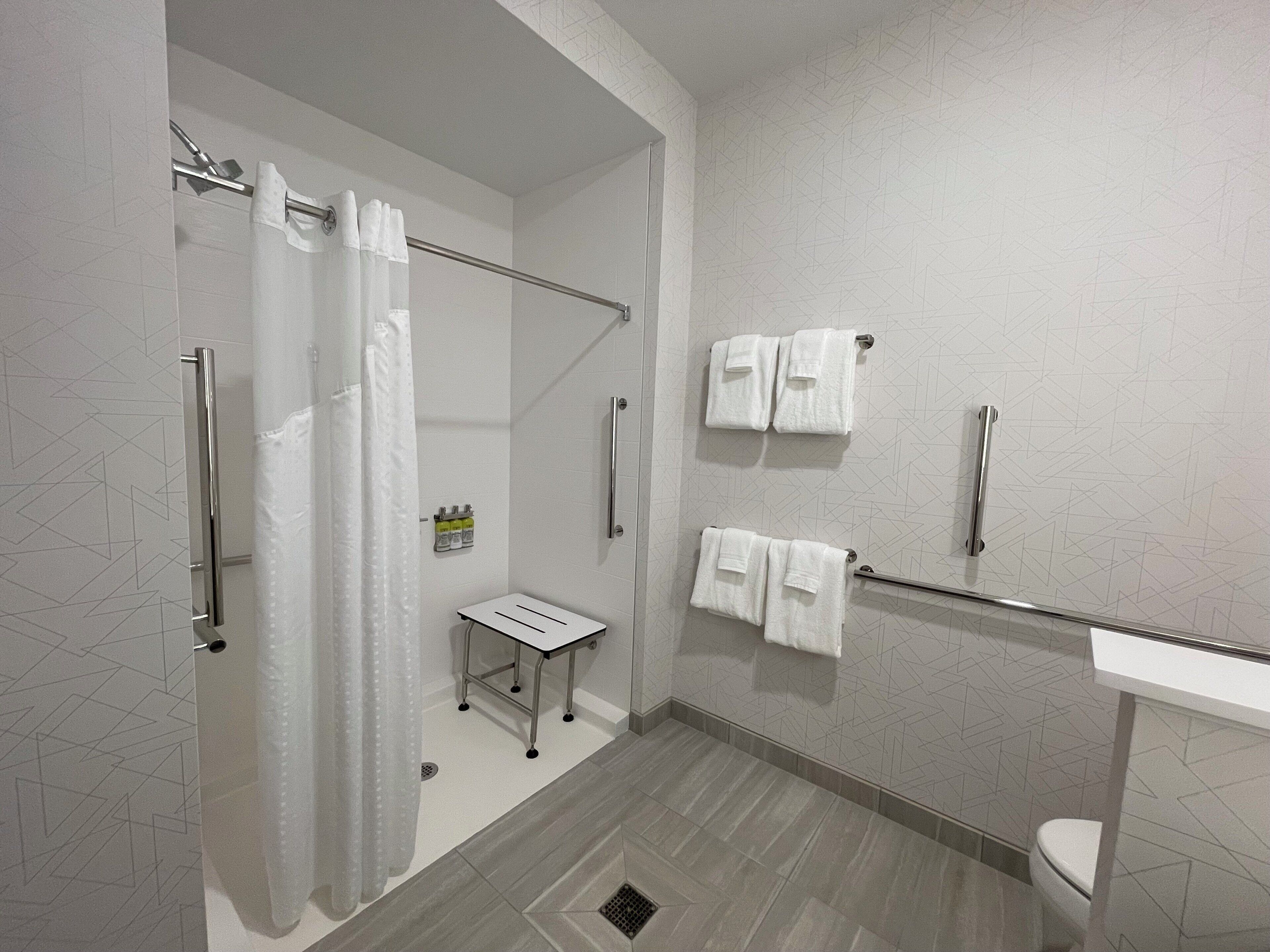 A modern bathroom with a shower, toilet, and a towel rack.