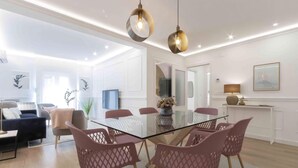 A modern dining area with a glass table, pink chairs, and pendant lighting. - Belvedere | The Rentals Collection (San Sebastián/Donostia)