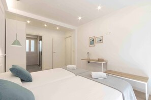 A bedroom with a bed, pillows, a bedside table, a hanging light, and a door leading to another room. - Belvedere | The Rentals Collection (San Sebastián/Donostia)