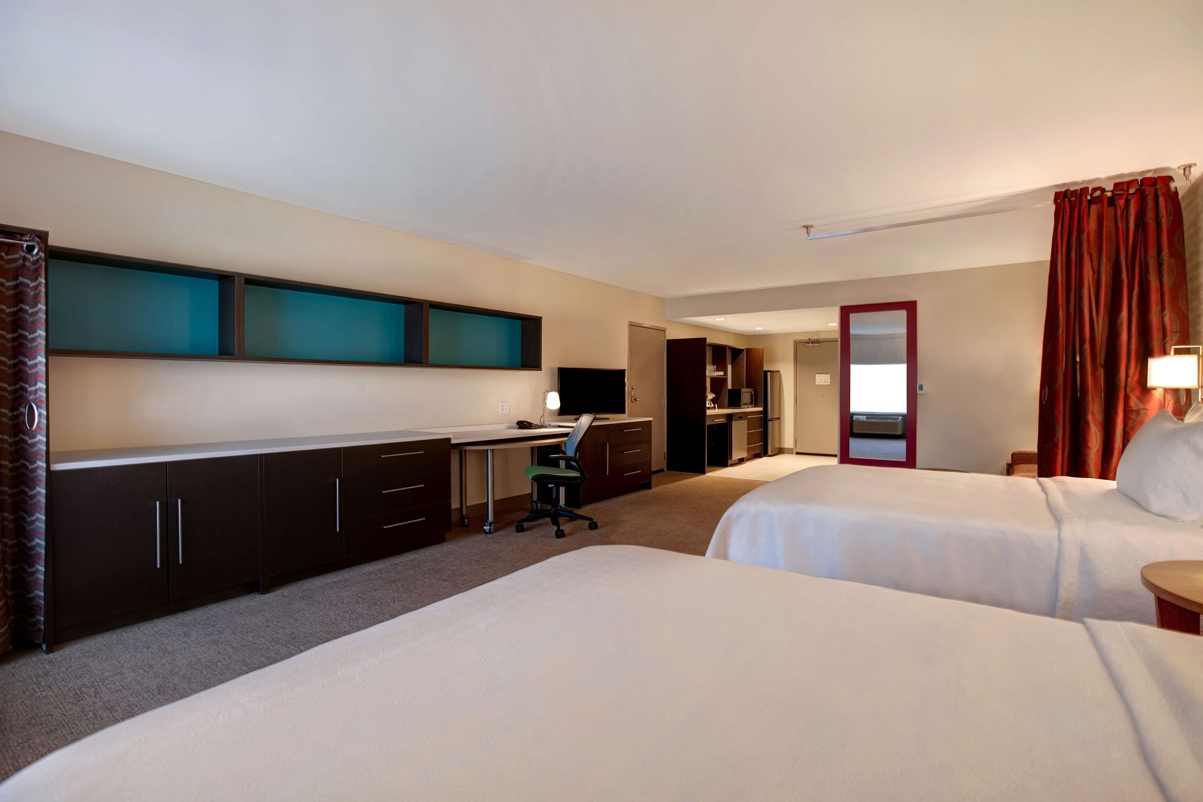 A hotel room with two beds, a desk with a computer, a chair, and a TV.