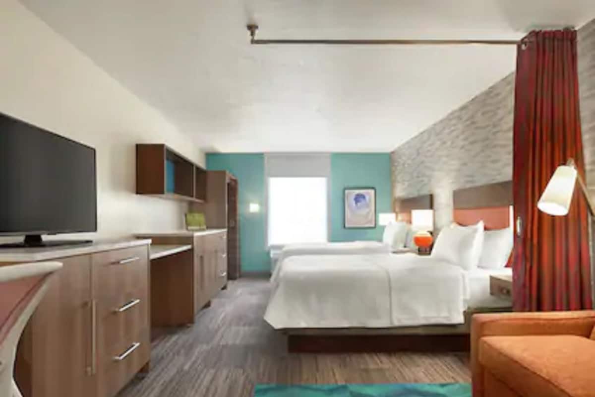 Una habitación de hotel con una cama, televisión, escritorio y silla.