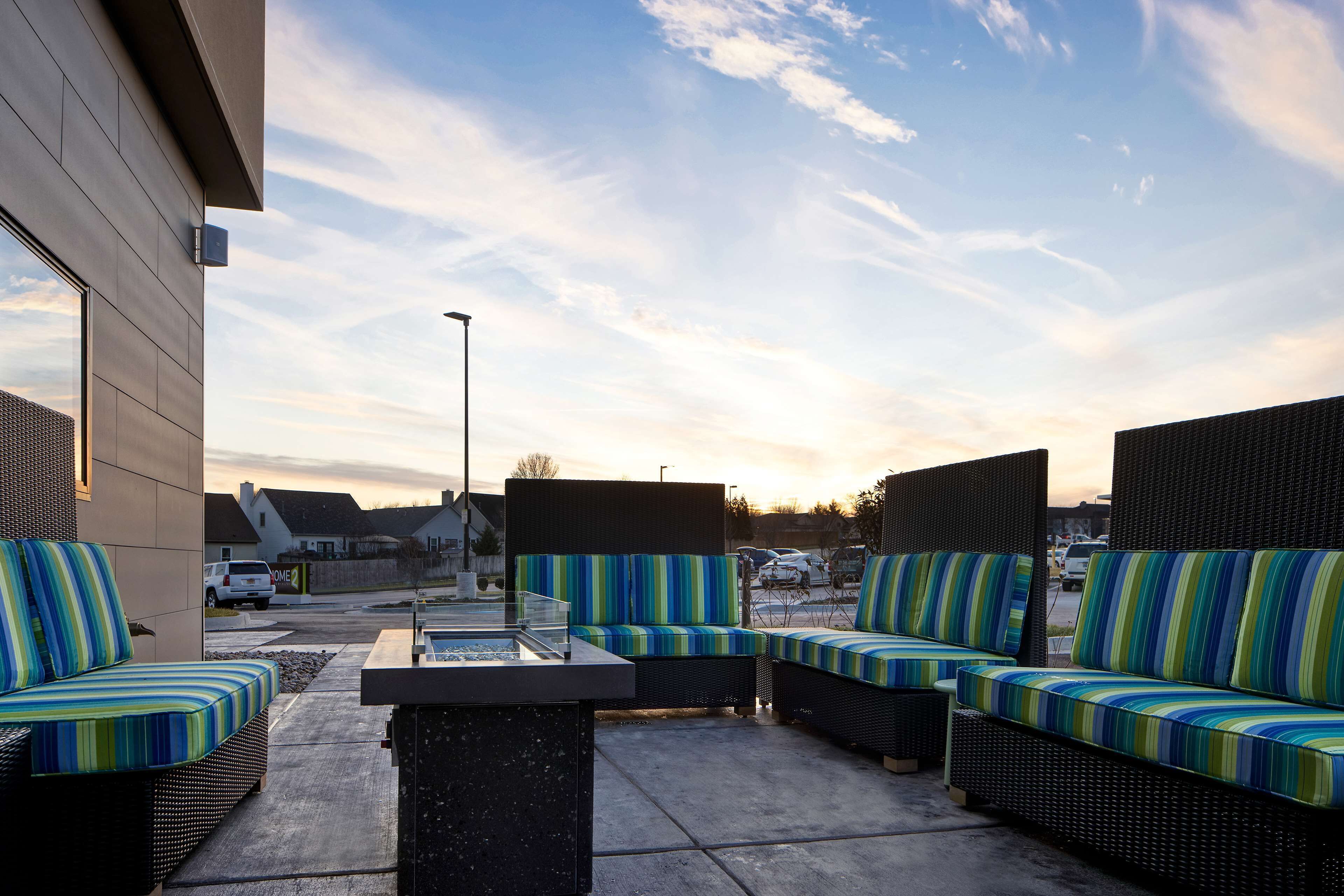 An outdoor seating area with wicker furniture and striped cushions, a fire pit, and a clear view of the sky.