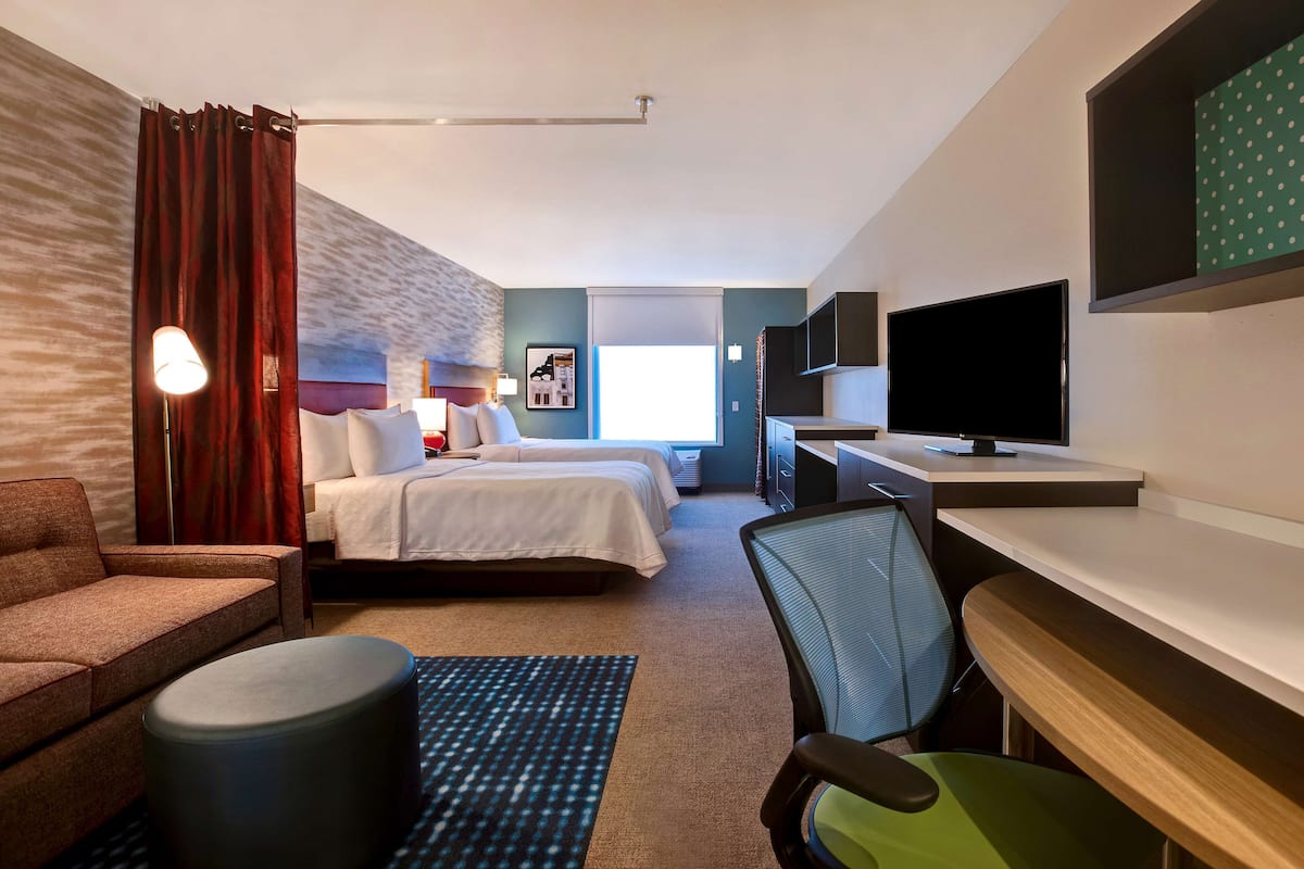 Habitación de hotel con cama, escritorio, silla, televisor y ventana.