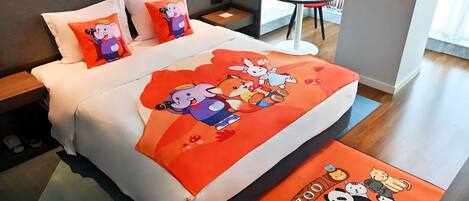 Quarto de hotel com cama, almofadas, uma mesinha, uma cadeira e um tapete.