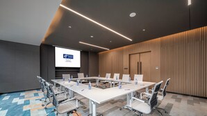 A conference room with a long table, chairs, a projector screen, and a presentation on the wall. - Holiday Inn Express Zhuhai Gongbei by IHG (Zhuhai)