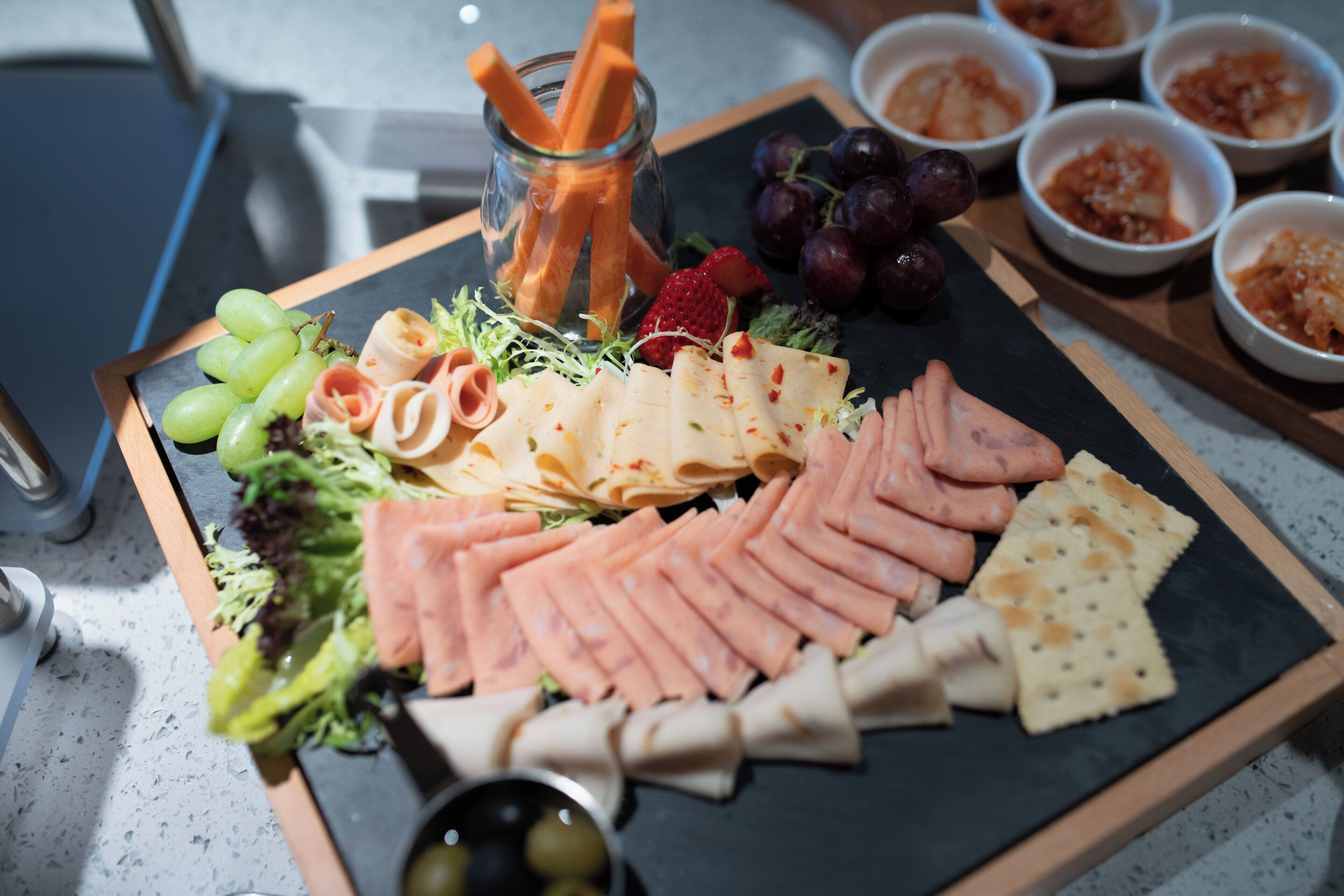 A charcuterie board with various meats, cheeses, and fruits.