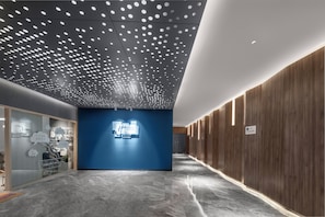 A hotel corridor with a blue wall, wooden paneling, and a ceiling with circular light fixtures. - Holiday Inn Express Zhuhai Gongbei by IHG (Zhuhai)