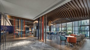 A modern interior with a mix of seating areas, large windows, and a unique ceiling design. - Holiday Inn Express Zhuhai Gongbei by IHG (Zhuhai)
