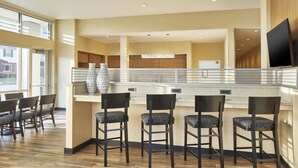 A modern kitchen with a bar area, wooden flooring, and a large window providing natural light. - TownePlace Suites by Marriott Columbus North - OSU (Columbus)
