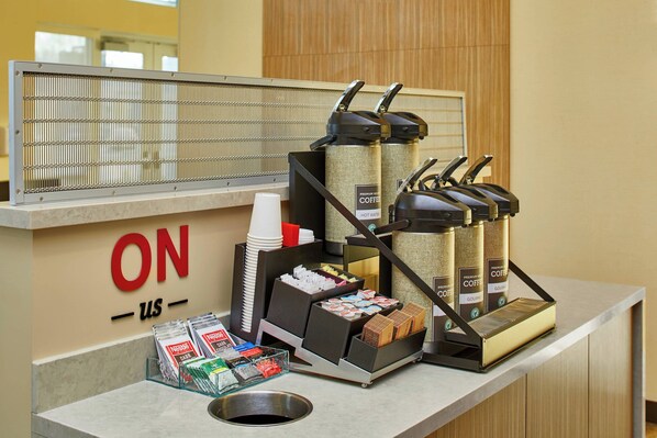 A coffee station with multiple coffee dispensers, a coffee cup holder, and a basket of coffee pods. - TownePlace Suites by Marriott Columbus North - OSU (Columbus)
