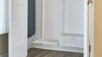 Um closet amplo com portas abertas, com uma estante de metal para pendurar roupas, um prateleira para guardar objetos e um suporte para sapatos.