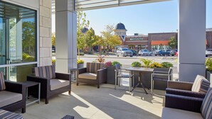 An outdoor seating area with wicker furniture and a view of a street with a Rusty Bucket store. - TownePlace Suites by Marriott Columbus North - OSU (Columbus)