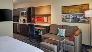 A hotel room with a bed, a sofa, a desk with a computer, a microwave, and a coffee maker. - TownePlace Suites by Marriott Columbus North - OSU (Columbus)