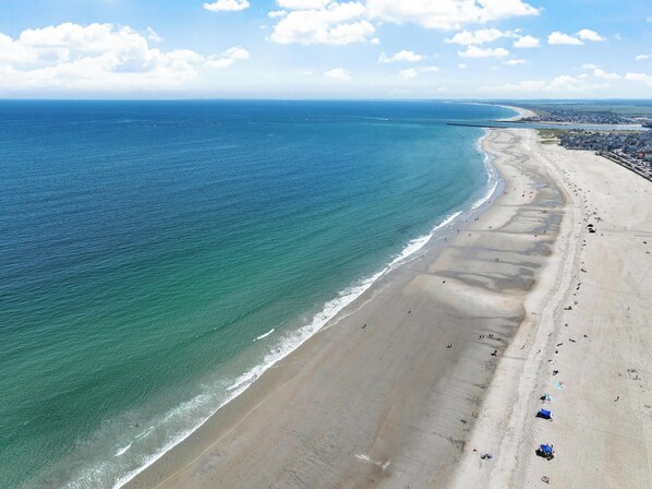A coastal beach with a wide sandy shore, gentle waves, and a clear sky.